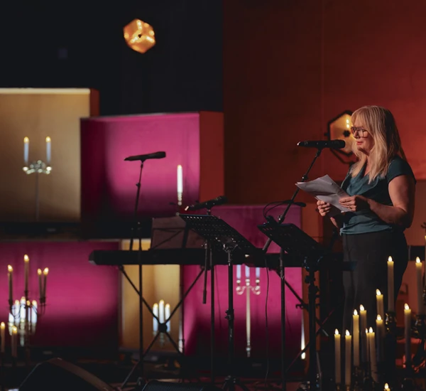 Forfatter Marit Eikemo står på en scene og leser fra en tekst omgitt av levende lyd. Foto.